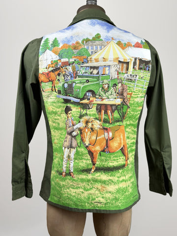 Dark Green Vintage Army Jacket 2 front button pockets. On back there is a bright happy scene featuring a horseshoe with a young child standing next to a small brown pony a judge sitting at a table in the background  as well as tents, oan old jeep and horses being led by other children. the sky is bright blue and you can see green trees I the distance.